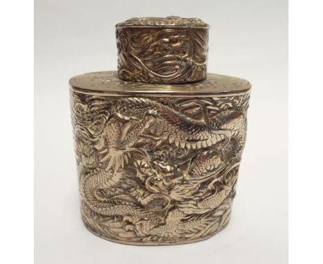 A Chinese white metal oval tea caddy embossed with dragons chasing pearls 11cms tall 