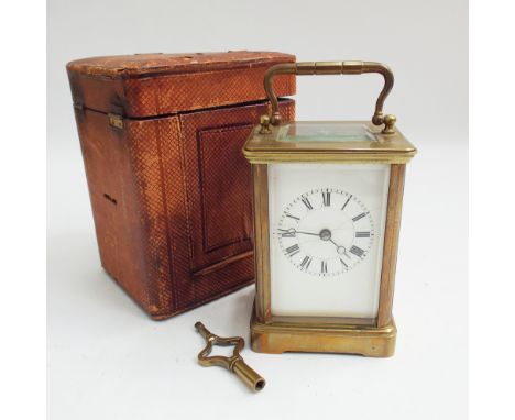 Brass and glass cased carriage clock, white enamel face, leather box and key 15cm high including handle   Condition - the ena