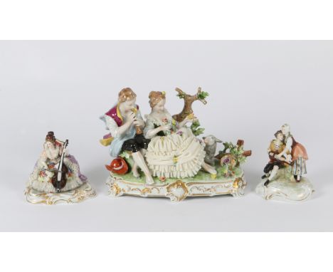 A CONTINENTAL PORCELAIN GROUP of a girl and a boy in a pastoral scene mounted on an oval base with gilt scrolling decoration 