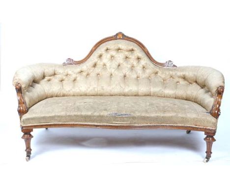 A VICTORIAN WALNUT FRAMED SOFA with shaped button upholstered back, inlaid decoration to the cresting rail and scrolling arm 