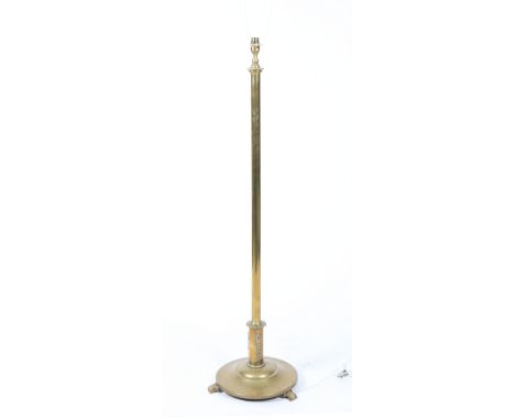 A BRASS LAMP STANDARD with column support and spreading circular base on three scroll feet 118cm high 