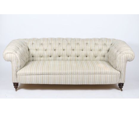 A VICTORIAN BUTTON BACK STRIPED UPHOLSTERED CHESTERFIELD SOFA with rollover arms and standing on short turned legs with brass