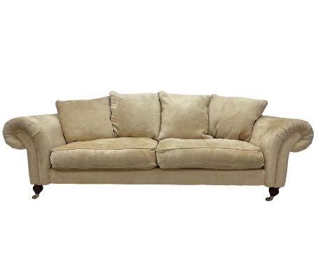 DFS - three seater sofa, upholstered in cream fabric, raised on turned and reeded supports, terminating in brass castors Dime