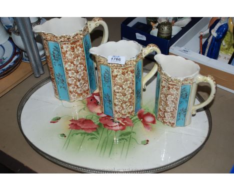 Three graduated Jugs in blue and brown floral pattern and a ceramic based Tray with white metal galleried rim, base cracked.