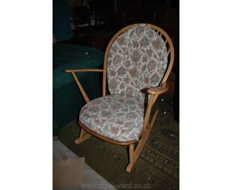 An Ercol stickback Rocking Chair with light beech frame, with back and seat cushions in cream ground floral pattern fabric