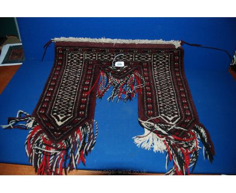 A red ground Carpet Tent hanging with white zig-zag decoration and red and black fringes.