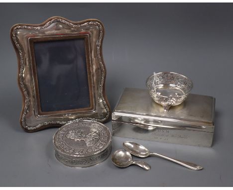 A silver cigarette box, a continental embossed silver box, a silver photo frame, a silver caddy spoon, silver dish and spoon.