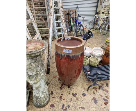 A tall red glazed garden planter.
