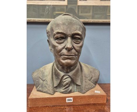 A bronze portrait bust of a gentleman indistinctly signed on his right shoulder and supported on a rectangular wooden plinth.