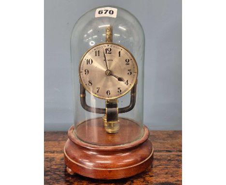 An early 20th-century Bulle-type electric battery mantle or desk clock on a wooden base beneath a glass dome.