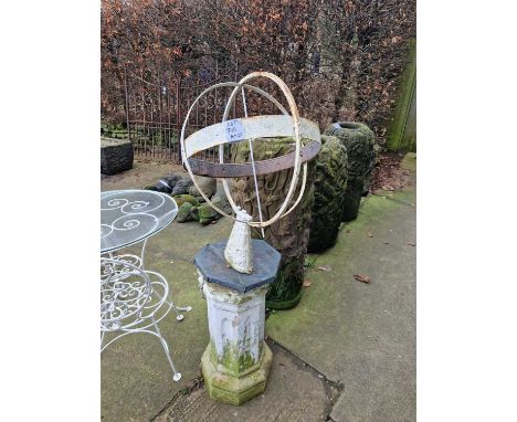 A vintage weathered sundial of armillary sphere form on a painted column support