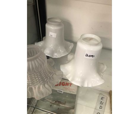 A pair of milk glass light shades together with another in frosted glass