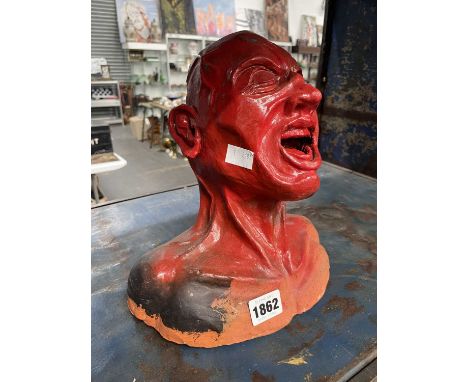 A red painted clay model of a male screaming head