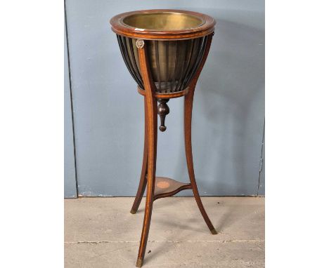 An Edwardian mahogany planter table with a brass liner, the three splay legs topped by brass lion's masks and joined by a ros