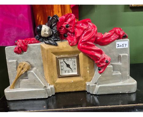 A battery driven mantel clock the plaster case modelled with a clown dressed in red sleeping across the top, his gilt mandoli