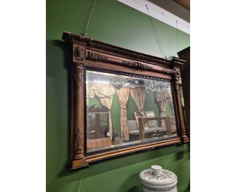 A 19th century gilt framed overmantle mirror with a reeded ebony slip and shelf base, the frame with gun barrel columns appli