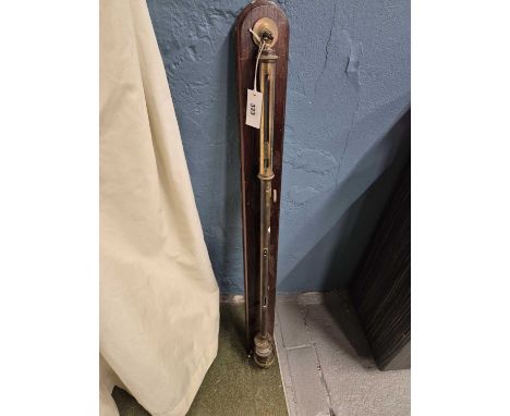 A brass stick barometer mounted onto a wooden back board