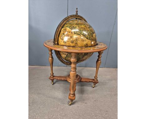 A terrestial globe drinks cabinet printed after a Spanish 1578 original and supported on four mahogany baluster legs