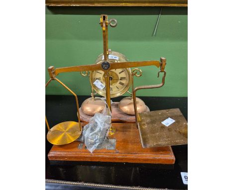 A brass cased mantel clock supported above two copper bells and together with a set of letter scales