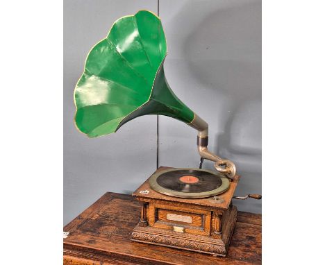 A vintage early 20th-century oak-cased tabletop gramophone with dark green and gold painted flared metal horn. The base with 