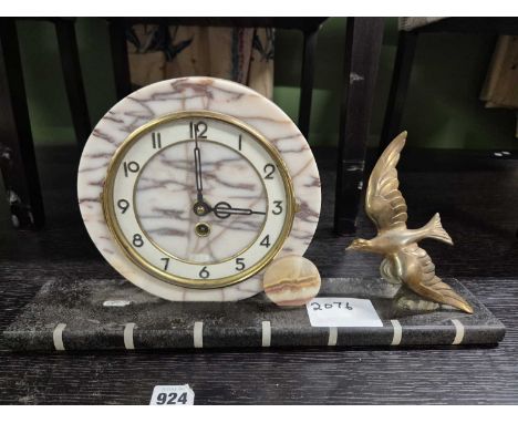 An Art Deco mantle clock with a gilt bird flying towards the circular marble mounted dial