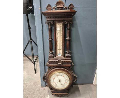 A Victorian oak cased aneroid barometer, the circular ceramic dial within a leaf nanded bezel below a mercury thermometer mou