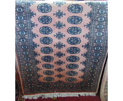 An Afghan style wool rug with pale pink field, multi medallion detail, set within running borders, 175 x 95 cm.