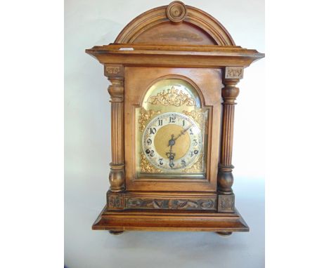 A late 19th century German walnut bracket clock, with broken arch dial, the case with column support and further carved detai