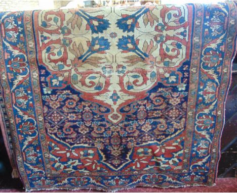 An old Persian wool work rug with pale cream floral medallion set within a further blue ground field and with alternating blu