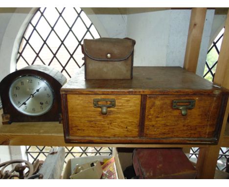 A two divisional oak bank of desk drawers with applied brass handles together with a veneered mantle clock marked Parsons Lim