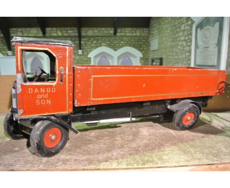 A large vintage model of a truck with painted tin bodywork and timber base, with red painted livery and gilded bordering, ste