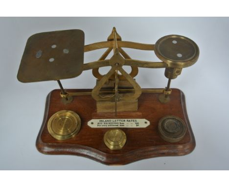 A set of vintage brass postal balance scales with postal rates (not exceeding 2 oz 1 1/2d) with three original weights