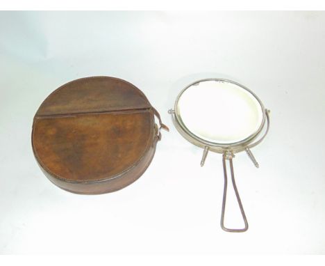 An early 20th century military shaving mirror of circular form with bevelled glass plate set within a swivelling silver plate