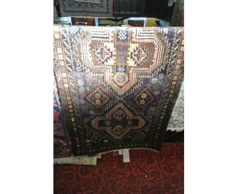 An eastern wool work rug with twin medallion centre upon a blue field with geometric detail set within running borders, 150 x