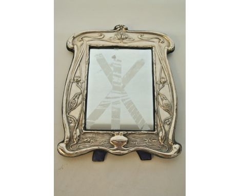 An Art Nouveau easel back mirror, William Neale, Birmingham, 1910, the shaped frame embossed with water lilies, birds, flower