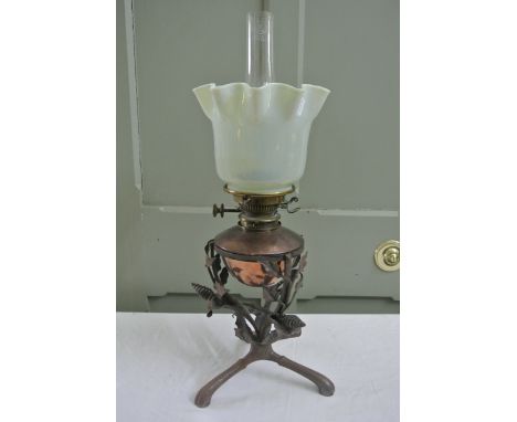 An Arts and Crafts style oil lamp the ironwork base with spread tripod supporting a floral framework (stamped to ring J G & C