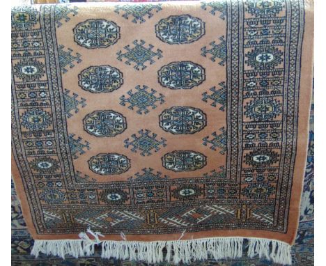 An Afghan style wool work rug with a pale pink field, multi medallion panels set within alternating borders, 165 x 95 cm.