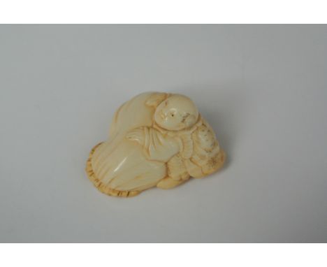 A late 19th century Chinese ivory netsuke, a character with a large rice sack