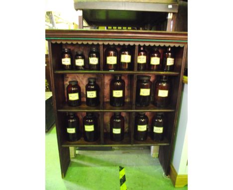 A 19th century stained pine wall shelf with segmented interior, containing a collection of eighteen chemists bottles in amber