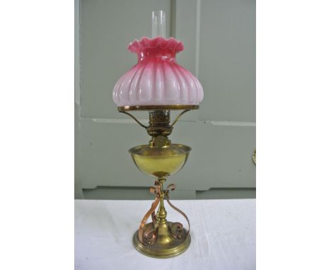 An Arts and Crafts oil lamp principally in brass with knopped stem, supporting three scrolled copper supports and disc shaped