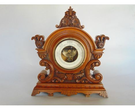 A late 19th century aneroid barometer, set within a flamboyant carved oak case with C-scroll, acanthus and other carvings.