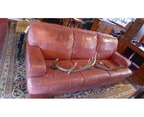 A mid 20th Century red leather three seater sofa, raised on chrome feet. 