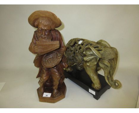 Carved wooden figure of a seated man, together with a ceramic figure of an elephant 