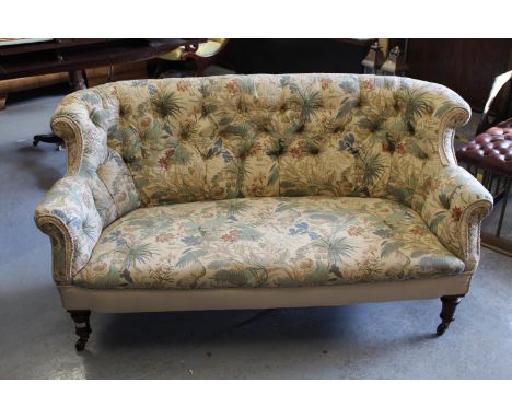 Victorian button upholstered two seat sofa, the rolled back above an overstuffed seat on turned tapering supports with brass 