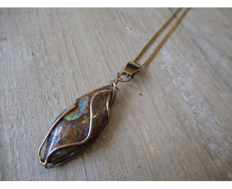 Boulder opal in a yellow metal pendant cage mount on chain 