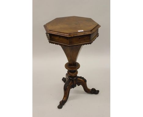 Victorian walnut octagonal trumpet form work table, the hinged lid enclosing a fitted interior on a carved tripod base 