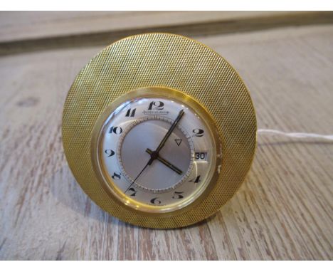 Small Jaeger le Coultre vintage gold plated travel alarm clock having engine turned decoration and a circular silvered dial w