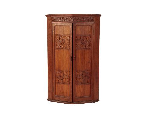 ARTS AND CRAFTS OAK CORNER CUPBOARD, the two doors decorated with four carved vine leaf panels, the top with a freize of carv