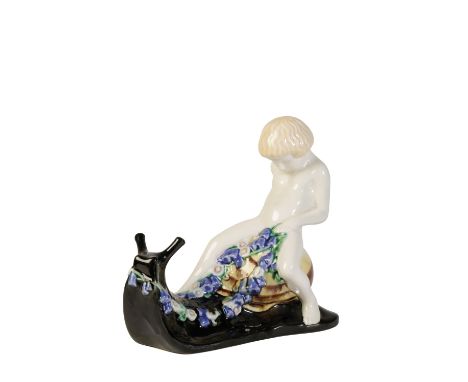 MICHAEL POWOLNY FOR WIENER WERKSTATTE: AN EARTHENWARE FIGURE, modelled as a cherub on a snail, glazed and painted in polychro