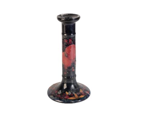WILLIAM MOORCROFT: A "POMEGRANATE" CANDLESTICK, cylindrical form, decorated in polychrome on a dark blue ground, on a spreadi